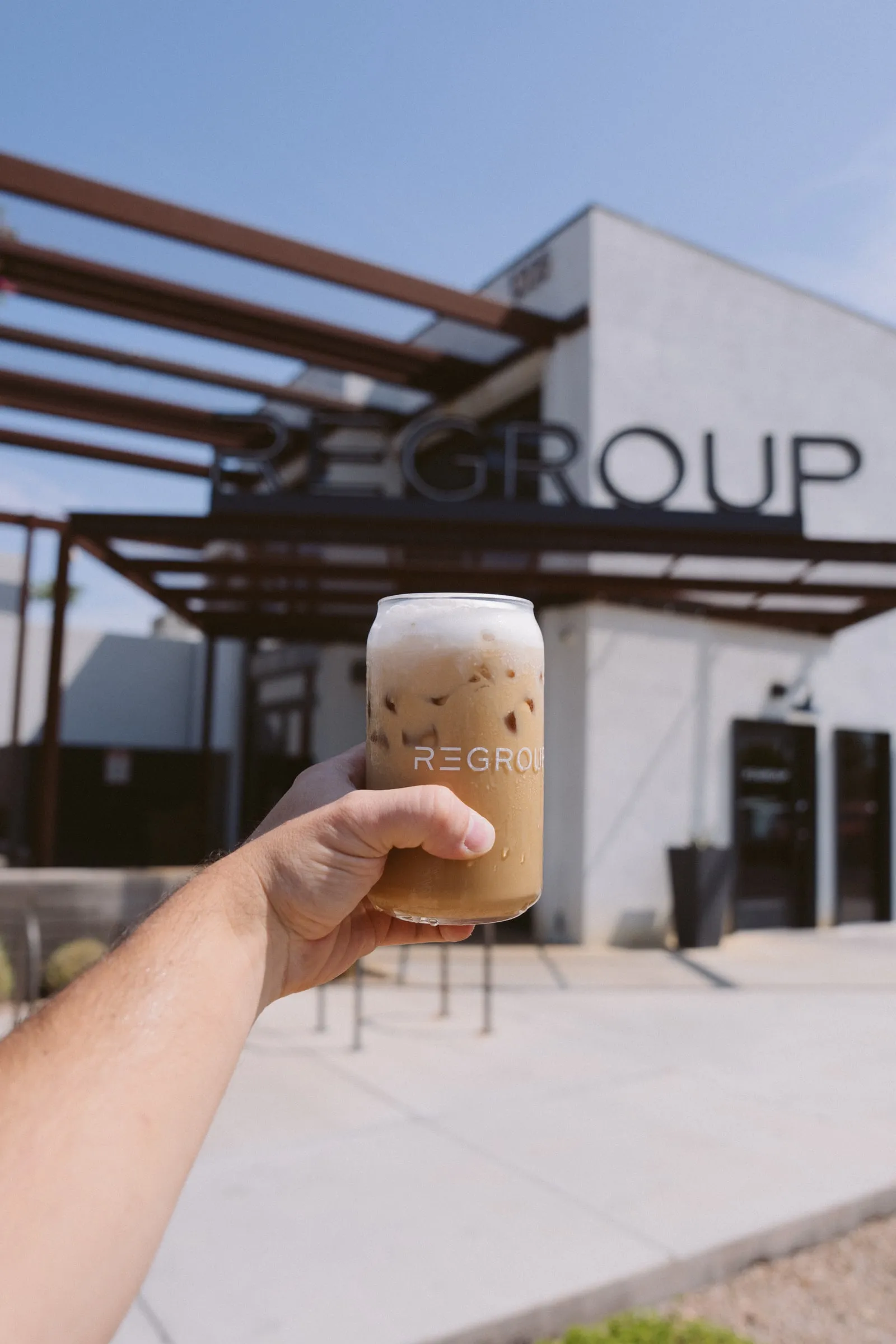 An iced coffee in a Regroup glass outside the shop.